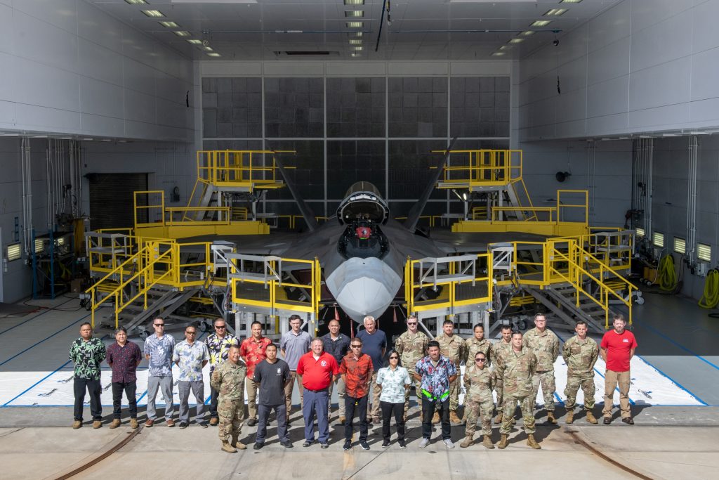 A team comprised of U.S. Air Force, Air National Guard, and contract personnel pose in front of their custom-designed F-22 Raptor maintenance stands during the debut event Sept. 26, 2024, at Joint Base Pearl Harbor-Hickam. The specialized maintenance stands are the culmination of nearly five years of collaboration between Total Force Airmen and the National Guard Bureau, providing a safer and more efficient way to access the hard-to-reach areas of one of the world’s most advanced stealth aircraft. (U.S. Air National Guard photo by Master Sgt. Mysti Bicoy)