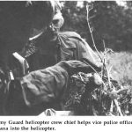 An Army Guard helicopter crew chief helps vice police officer load marijuana into the helicopter.