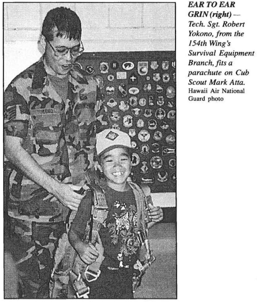 EAR TO EAR GRIN (right) Tech. Sgt. Robert Yokono, from the 154th Wing's Survival Equipment Branch, fits a parachute on Cub Scout Mark Atta. Hawaii Air National Guard photo