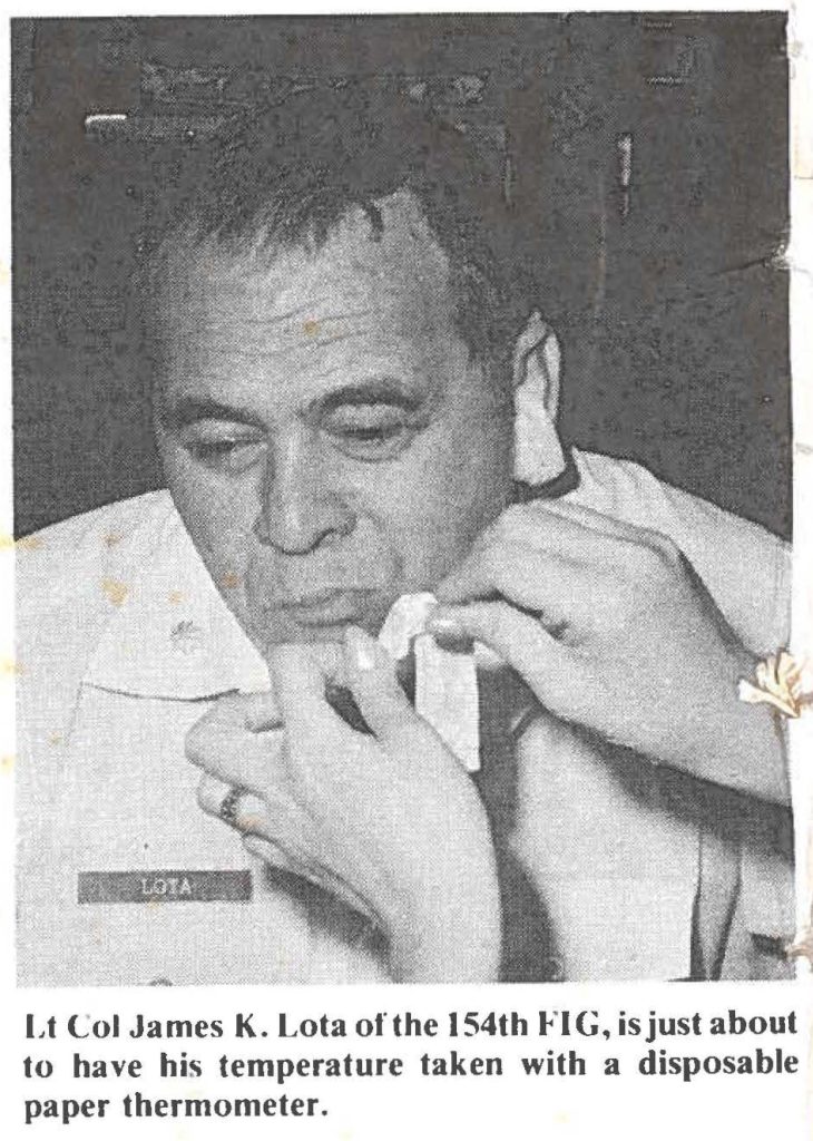 Lt Col James K. Lota of the 154th FIG, is just about to have his temperature taken with a disposable paper thermometer.