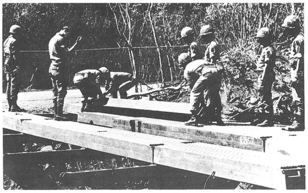 Members of the 227th Eng. Co. pitch in to lift into place a balk. The construction M4T6 Dry Span Bridge was one of only three bridge projects which the 227th was constructing simultaneously