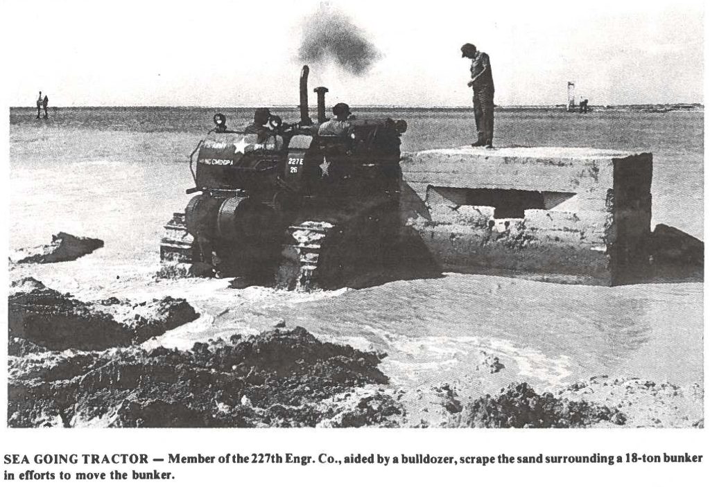 SEA GOING TRACTOR - Member of the 227th Engr. Co., aided by a bulldozer, scrape the sand surrounding a 18-ton bunker in efforts to move the bunker.