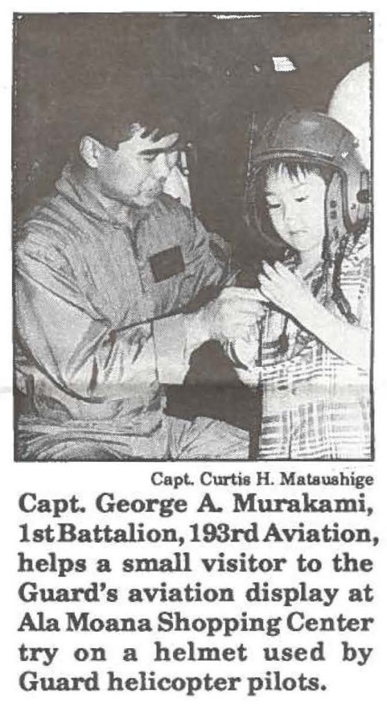 Capt. George A. Murakami, 1st Battalion, 193rd Aviation, helps a small visitor to the Guard's aviation display at Ala Moana Shopping Center try on a helmet used by Guard helicopter pilots.
