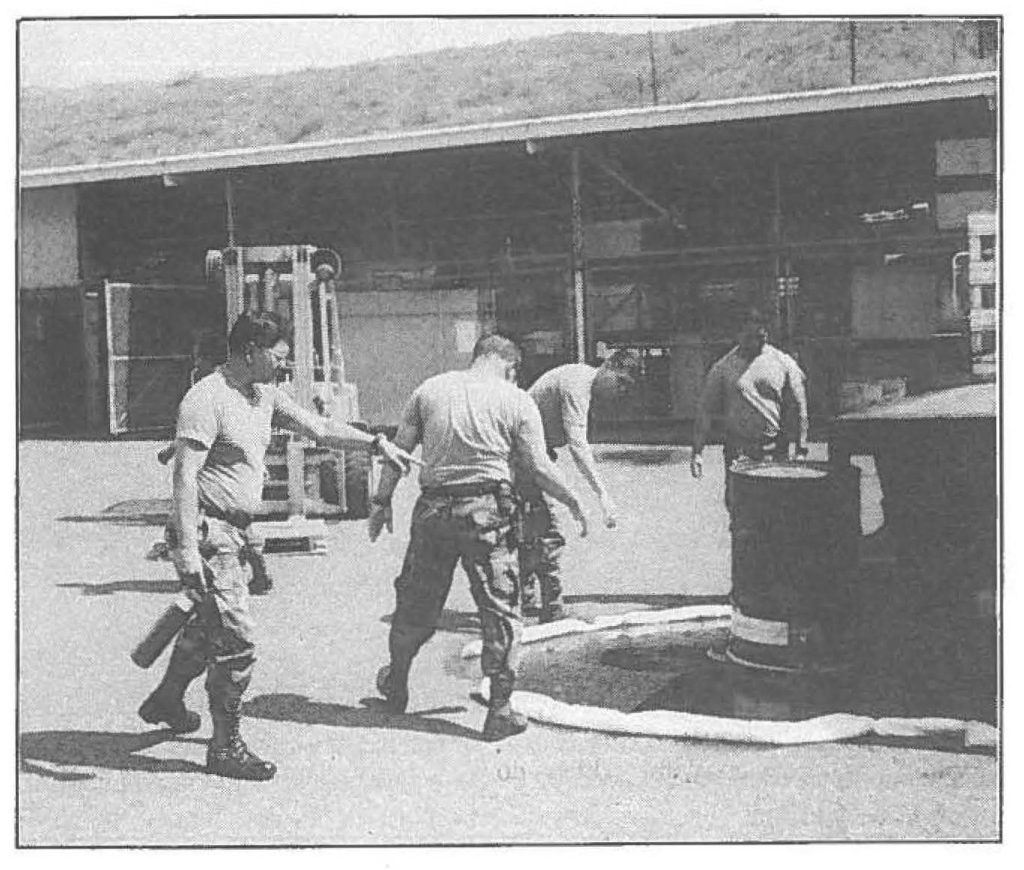 IT'S A WHOPPER! - Hawaii Army National Guard members (L-R) Spec. Gary Costales, Command Sgt. Maj. Francisco Latorre. Jr., Sgt. Carty Raquedan, Sgt.1st Class Leslie Yamamoto, Spec. Albert Makanani, and Master Sgt. Al Wong hurry to contain a simulated spill when this 55 gallon drum "fell" off its pallet while being loaded on a flatbed truck. The exercise was an annual awareness refresher course on hazardous waste operations and emergency response, or HAZWOPER.