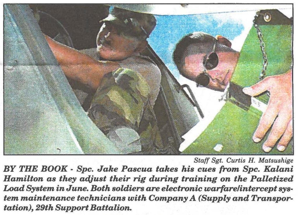 BY THE BOOK - Spc. Jake Pascua takes his cues from Spc. Kalani Hamilton as they adjust their rig during training on the Palletized Load System in June. Both soldiers are electronic warfare/intercept system maintenance technicians with Company A (Supply and Transportation), 29th Support Battalion.