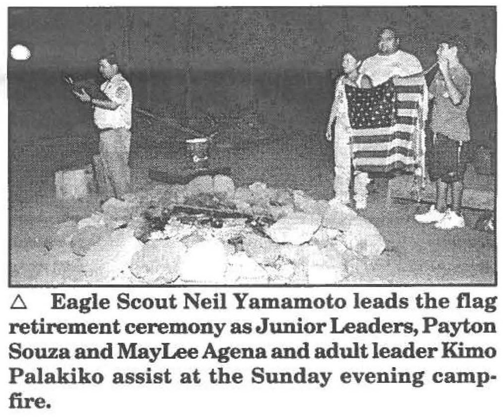 Eagle Scout Neil Yamamoto leads the flag retirement ceremony as Junior Leaders, Payton Souza and MayLee Agena and adult leader Kimo Palakiko assist at the Sunday evening campfire.