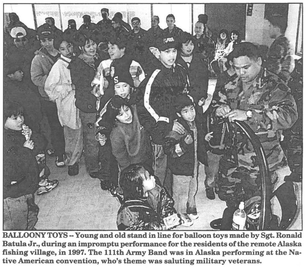 BALLOONY TOYS - Young and old stand in line for balloon toys made by Sgt. Ronald Batula Jr., during an impromptu performance for the residents of the remote Alaska fishing village, in 1997. The 111th Army Band was in Alaska performing at the Native American convention, who's theme was saluting military veterans.