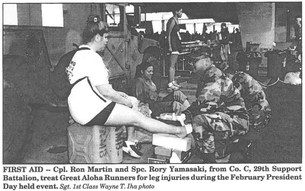 FIRST AID -- Cpl. Ron Martin and Spc. Rory Yamasaki, from Co. C, 29th Support Battalion, treat Great Aloha Runners for leg injuries during the February President Day held event. Sgt. 1st Class Wayne T. Iha photo