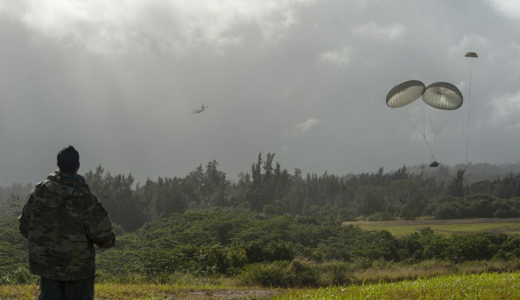 Tech. Sgt. Paul Roberts, 204th Airlift Squadron loadmaster, observes a parachute drop at the Kane’s drop-zone Jan. 14, 2020, at Kahuku, Hawaii. The training drop was part of Exercise H20 which focuses on interoperability between Hawaii and Alaska Air National Guard units, tasked with executing contingency astronaut rescue for NASA’s SpaceX Commercial Crew Program. Roberts was serving as the drop zone officer for the operation. (U.S. Air National Guard photo by Staff Sgt. Orlando Corpuz)