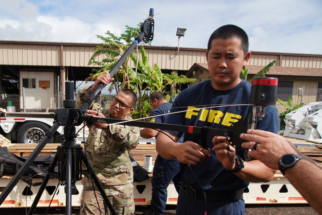 Sgt. 1st Class Elizaldy Pantil, Hawaii National Guard 93rd WMD-CST, assists members of the Kauai Fire and Police departments in the set-up of an antenna array during emergency communication training, Kauai, Hawaii, July 08, 2021. The Hawaii National Guard 93rd WMD-CST conducted joint training with Kauai emergency response agencies including the Kauai Fire Department, Kauai Police Department and Hawaii Department of Health to refine and enforce the Hawaii counties response interoperability in a natural or man-made Hazardous Material (HAZMAT) or Chemical, Biological, Radiological, Nuclear (CBRN) incident. (U.S. Air National Guard photo by Master Sgt. Andrew Jackson)