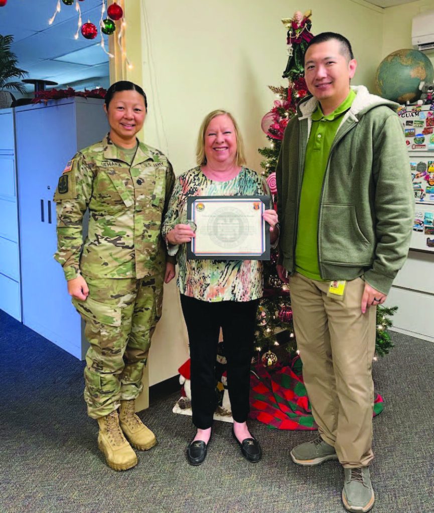 Lt. Col. Doreen Uehara and Mr. Galen Kan present a USPFO certificate of appreciation and coin to Kathleen Carreira, Travel Experience Counselor II, CWT Sato Travel, for her support and excellent customer service while coordinating 900 commercial flights from Honolulu and Hilo to Louisiana to support the 29th Infantry Brigade Combat Team’s training exercise at Fort Johnson. – Lt. Col. Doreen Uehara photo