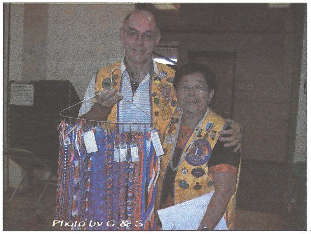 Mark Despault, president of the Mililani Lions Club, and Shirley Ito, Hilo Lions Club member, prepare to distribute red, white, and blue ribbons and yarn leis to the returning soldiers during a welcome home ceremony for members of the 29th Brigade Combat Team.