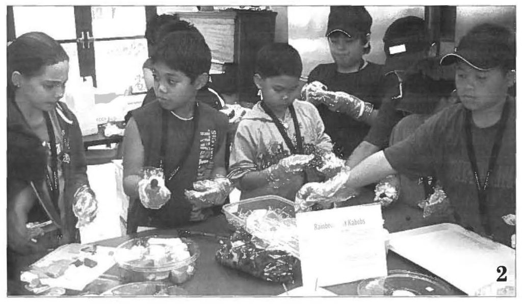Participants make fruit kabobs during the 4-H Club session.