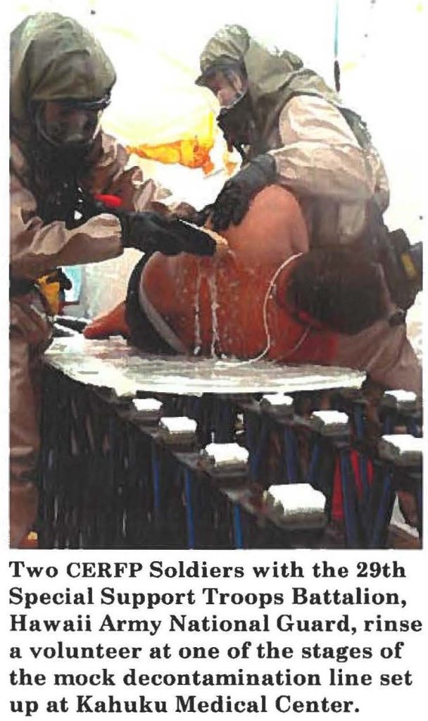 Two CERFP Soldiers with the 29th Special Support Troops Battalion, Hawaii Army National Guard, rinse a volunteer at one of the stages of the mock decontamination line set up at Kahuku Medical Center.