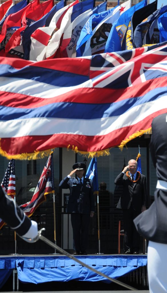 Maj. Gen. Darryll D.M. Wong, former Hawaii State adjutant general and retired Gen. Craig McKinley, former chief, National Guard Bureau, salute the Hawaii state flag during a retirement ceremony at the Distinguished Visitors reception area on Joint Base Pearl Harbor-Hickam, Hawaii, April 12, 2015. The Royal Guard, consisting of members of the Hawaii Air National Guard, present the colors for the ceremony. (U.S. Air Force photo by Airman 1st Class Robert Cabuco/Released)