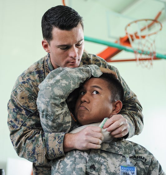 Fleet Marine Force (FMF) Hospital Corpsman 2nd Class Joshua Rogers, assigned to 3rd Medical Battalion and Sergeant Gerald Mina, assigned to the Hawaii National Guard, demonstrate proper hemorrhage control to members of the Mongolian Armed Forces during a casualty control familiarization class as part of Khaan Quest 2016 in Mongolia