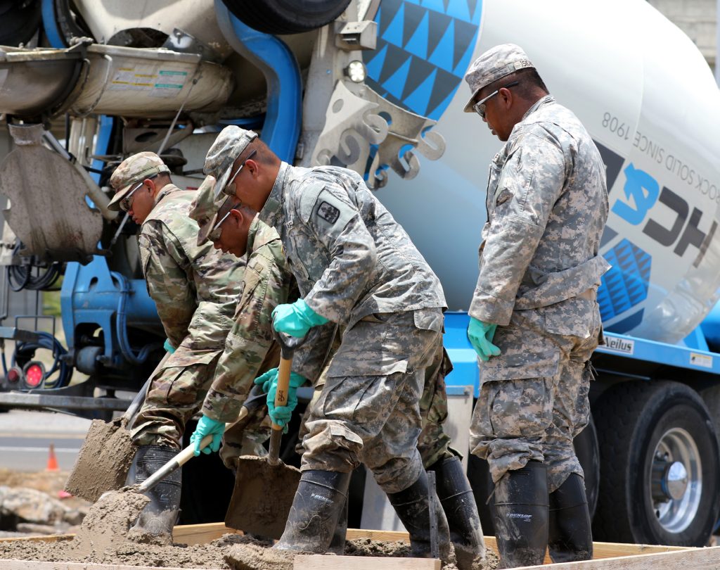 Hawaii National Guard Soldiers of the 227th Brigade Engineer Battalion, Alpha Company, work together to pave a foundation for housing in the Kahauiki Village project in Honolulu, Hawaii on Aug. 9, 2017. The project is a joint effort between private contractors and the State of Hawaii to build a community for homeless families. (U.S. Army National Guard Photo by Spc. Paul Berzinas)