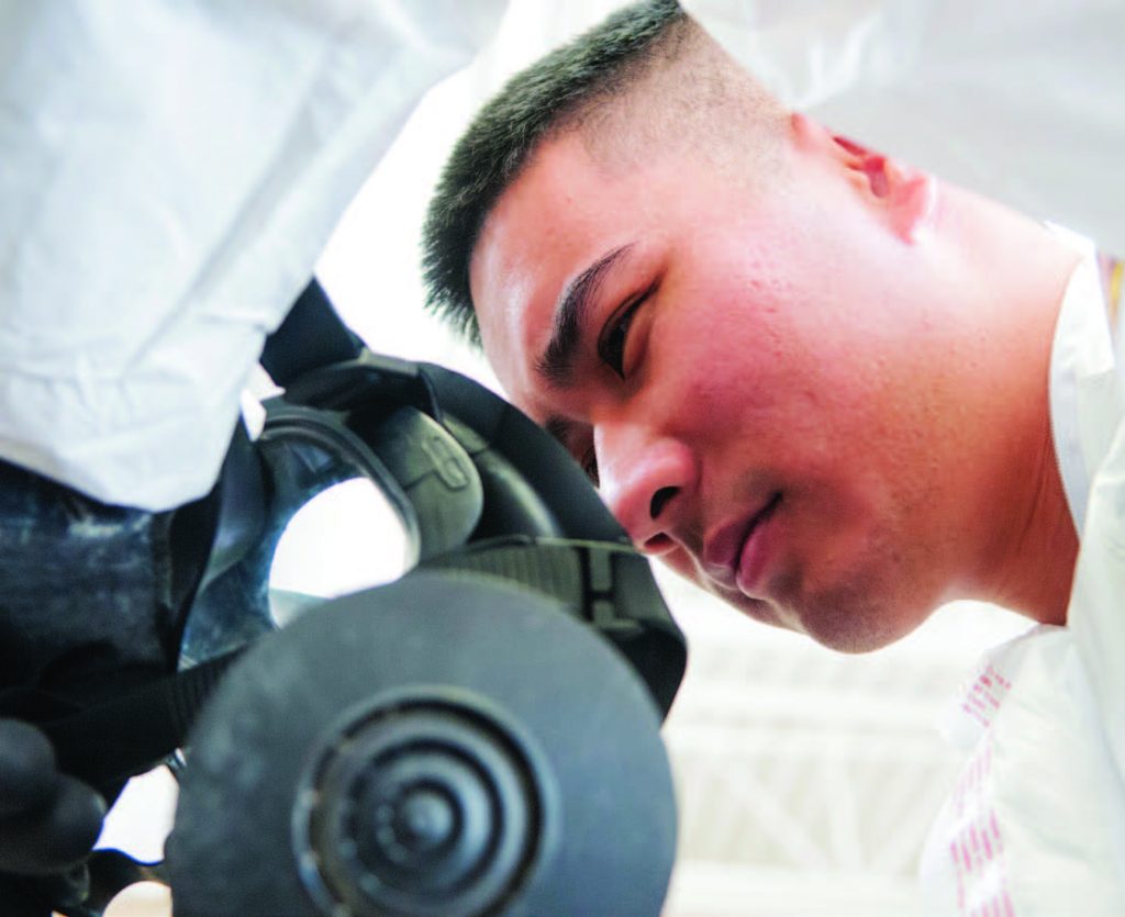 Senior Airman Nicklaus Young, an aerospace medical technician with the Detachment 1, 154th Medical Group, dons his gas mask at a Medical Capabilities exercise held in North Las Vegas, Jan. 27, 2018. (U.S. Air National Guard photo by Senior Airman Orlando Corpuz)