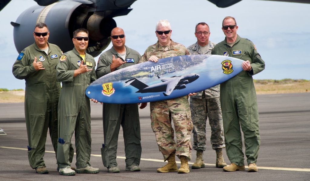 Left to right, Lt. Col. Jhonny Polanco, Deputy Director ANG Forces, HQ PACAF, Col. James Shigekane, vice commander, 154th Wing, Col. Phillip Mallory, commander, 298th Air Defense Group, Lt. Gen. L. Scott Rice, director of the Air National Guard, Col. Dann Carlson, director A5/8, HQ HIANG, Maj. Gen. David Burgy, Air National Guard assistant to COMPACAF poses for a photo with the 204th Airlift Squadron surfboard on June 21, 2019 at Barking Sands, Kauai. During his visit, he met with and recognized members of the organization and also held two Town Hall meetings where he addressed current and future events with The Guard. (U.S. Air National Guard photo by Staff Sgt. James Ro)