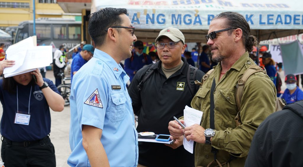 Hawaii Emergency Management representative David Lopez, and Hawaii National Guard disaster response manager Maj. Wayne Anno provide exercise control input to Mike Marasigas, Incident Commander from Quezon City Disaster Risk Reduction Management Council, during the initial response to an earthquake drill at the beginning of the field training exercise phase of the Community Disaster Readiness Exercise, Batasan Hills, March 27, 2019. (U.S. Air National Guard Photo by Tech. Sgt. Andrew Jackson