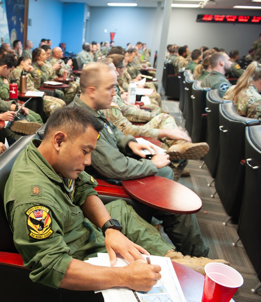 U.S. Army and U.S. Air Force service members are briefed on the schedule of events for the Joint Pacific Multinational Readiness Center Oct. 30, 2023 at March Air Reserve Base, California. Operating alongside our Allies and Partners at JPMRC 24-01 demonstrates our unity, will, and collective commitment. (U.S. Air National Guard photo by Airman 1st Class Roann Gatdula