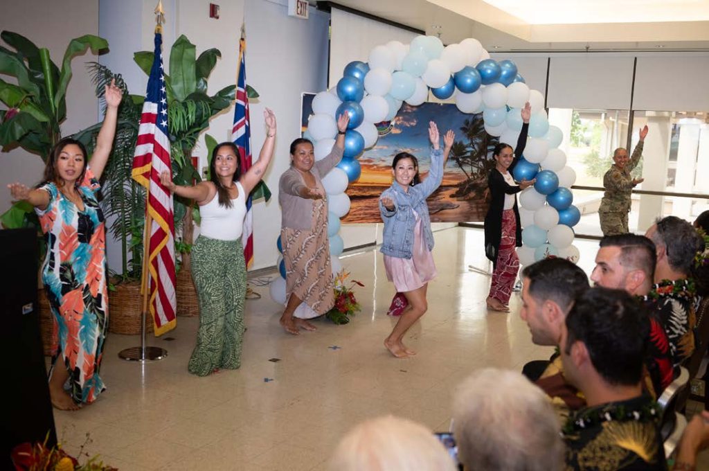 Hawai‘i Air National Guard members dedicate a hula performance to Lorna Souza, Hawai‘i Air National Guard Airman and Family Readiness coordinator, during her retirement ceremony Aug. 23, 2024, at Joint Base Pearl Harbor-Hickam, Hawai‘i. The hula was a heartfelt tribute to Souza’s embodiment of the Aloha spirit and her lasting impact on the HIANG ohana. Her nurturing presence earned her the beloved title of “Auntie” throughout the organization. Below, Auntie Lorna spoke at the ceremony (U.S. Air National Guard photo by Tech. Sgt. John Linzmeier)