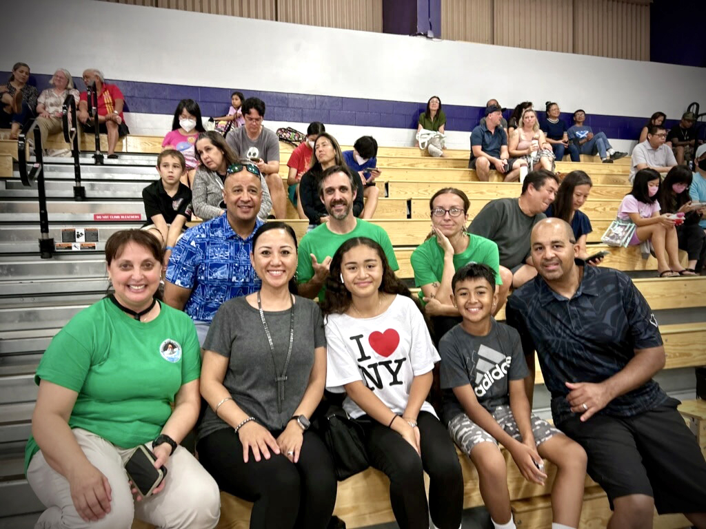 STARBASE Hawai‘i coaches (in green) Heather Leite, left, Ken Smith and Aly Clark sat with Deputy Adjutant General Brig. Gen. Phillip Mallory, top left, and Hawai‘i Air National Guard Senior Enlisted Leader Chief Master Sgt. Mey Martin, second from front left, and family at the Hawaii VEX IQ State Championships at Pearl City High School in February. (Marlise Ahuna photo)