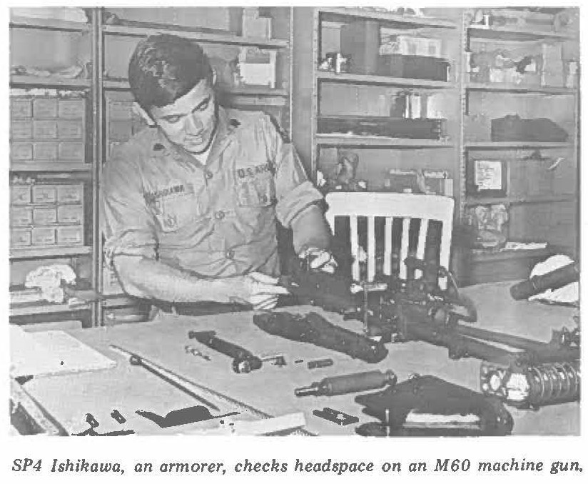 SP4 Ishikawa, an armorer, checks headspace on an M60 machine gun.