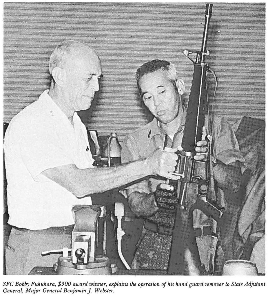 SFC Bobby Fukuhara, $300 award winner, explains the operation of his hand guard remover to State Adjutant General, Major General Benjamin J. Webster.