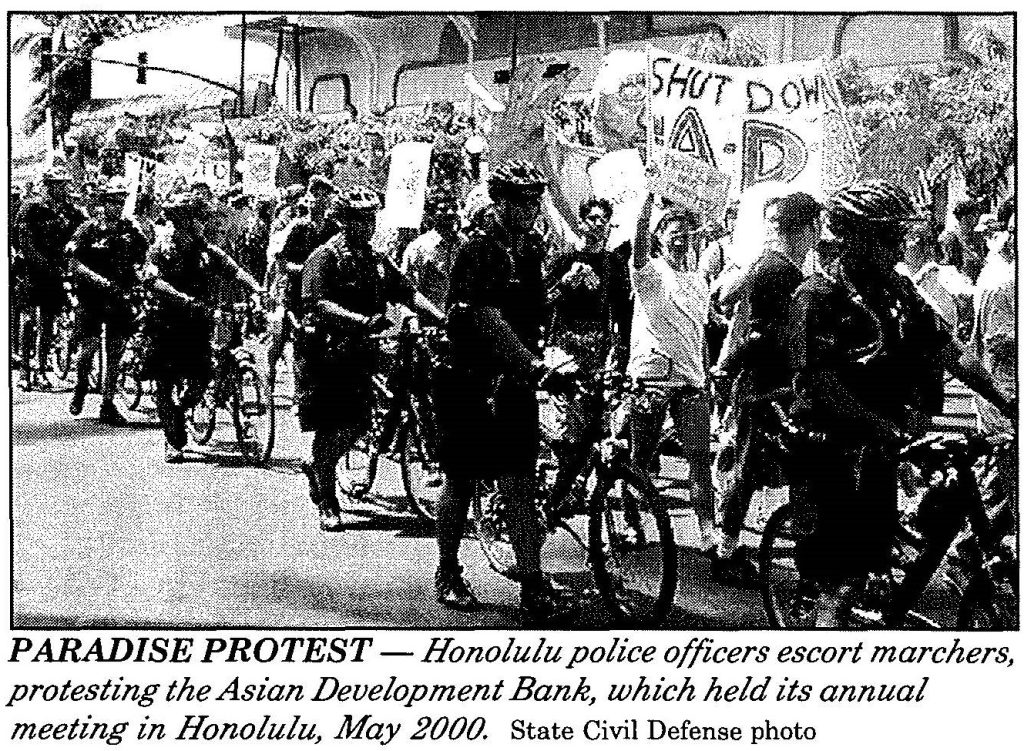 PARADISE PROTEST - Honolulu police officers escort marchers, protesting the Asian Development Bank, which held its annual meeting in Honolulu, May 2000. State Civil Defense photo