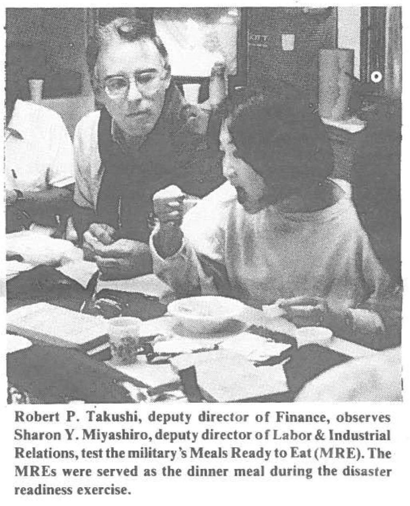 Robert P. Takushi, deputy director of Finance, observes Sharon Y. Miyashiro, deputy direct or or Labor & Industrial Relations, test the military's Meals Ready to Eat (MRE). The MREs were served as the dinner meal during the disaster readiness exercise.
