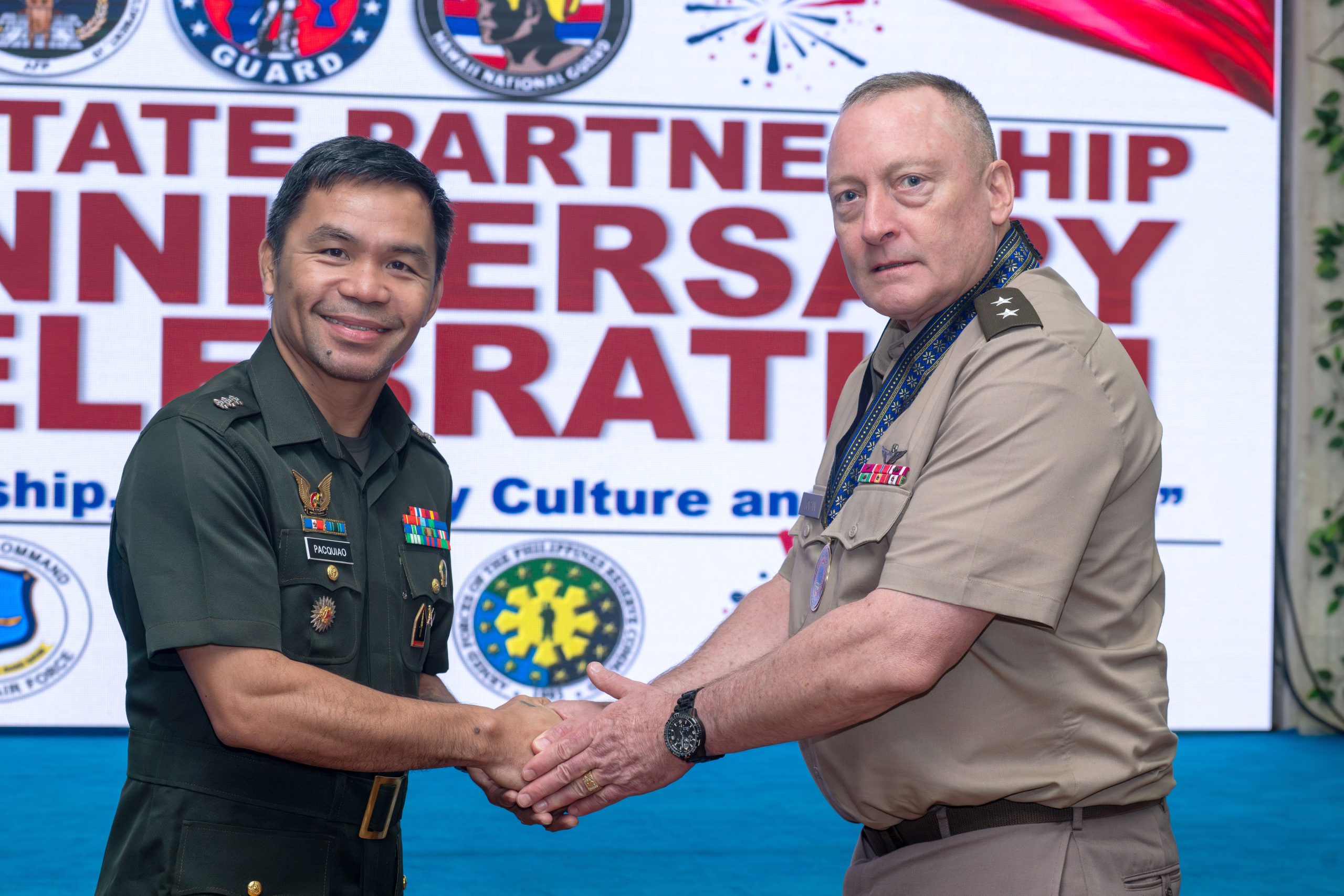 Philippine Air Force Reservist Col. Emmanuel “Manny” Pacquiao, left, received a commemorative coin from Maj. Gen. Stephen Logan during the 25th anniversary celebration of the State Partnership Program at Clark Air Base. (Hawai‘i Air National Guard photo by Senior Master Sgt. Mysti Bicoy)