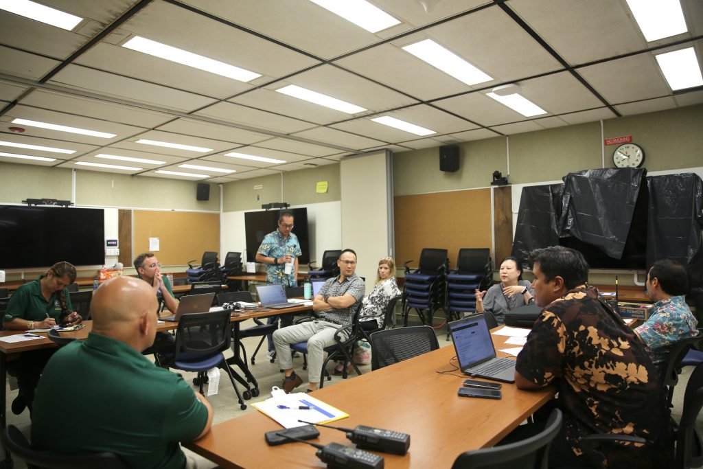 Above, Miyoke Ng discussed the activation exercise with her State of Hawai‘i Department of Accounting and General Services (DAGS) colleagues. Below, the DAGS Department Operations Center crew and Hawai‘i Emergency Management Agency (HIEMA) observers gathered for a photo. (HIEMA photos)
