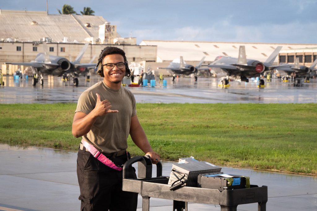 a U.S. Air Force maintenance Airman assigned to the 15th Maintenance Group flashed a shaka while transporting equipment during Sentry Aloha 26-1 at Joint Base Pearl Harbor-Hickam on Jan. 14. (U.S. Air National Guard photo by Tech. Sgt. John Linzmeier)