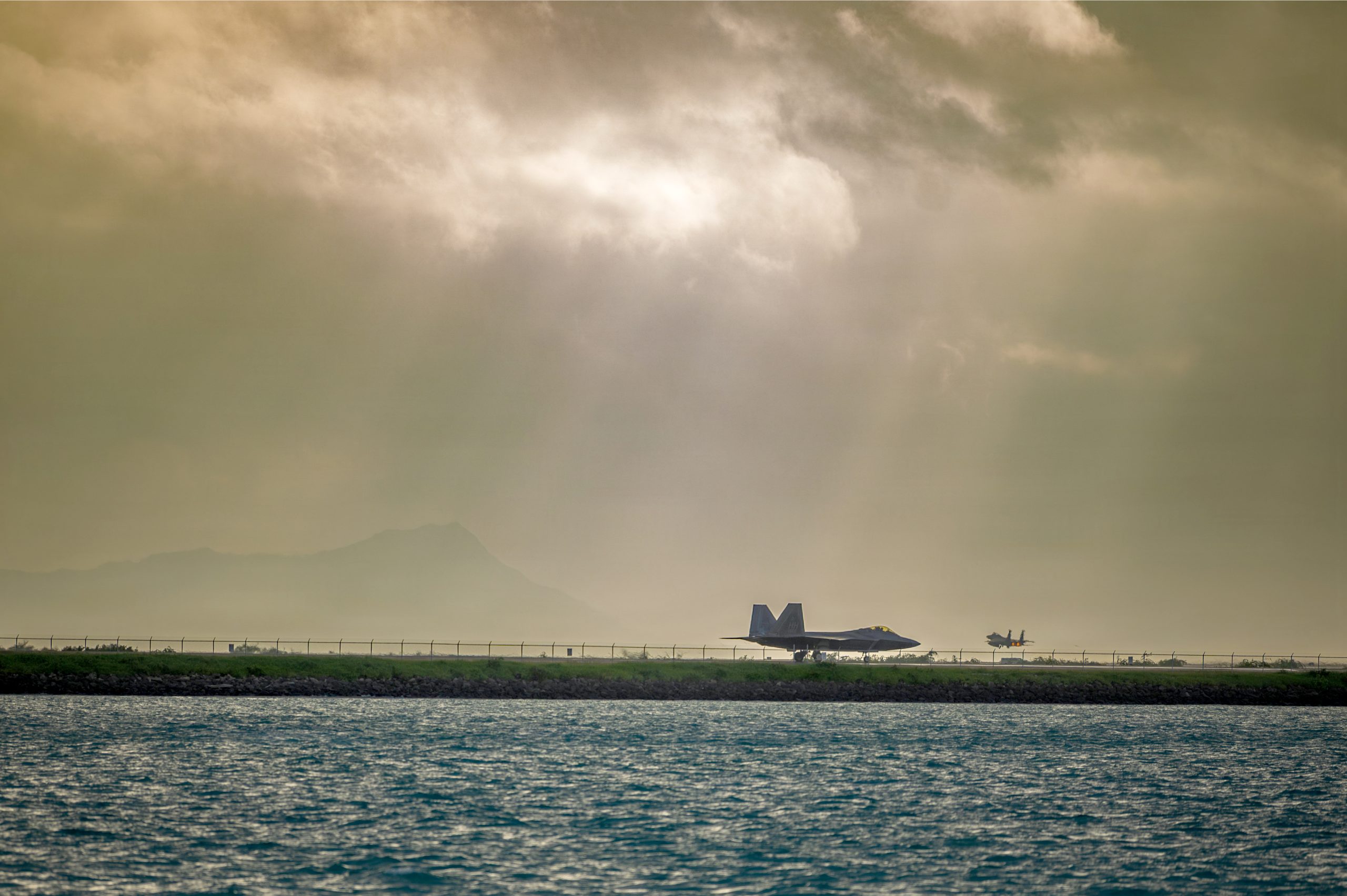 a U.S. Air Force F-22 Raptor assigned to the 199th Fighter Squadron taxied while an F-15 Eagle took off during Sentry Aloha 26-1 at Daniel K. Inouye International Airport on Jan. 14 (U.S. Air National Guard photos by Senior Master Sgt. Mysti Bicoy)