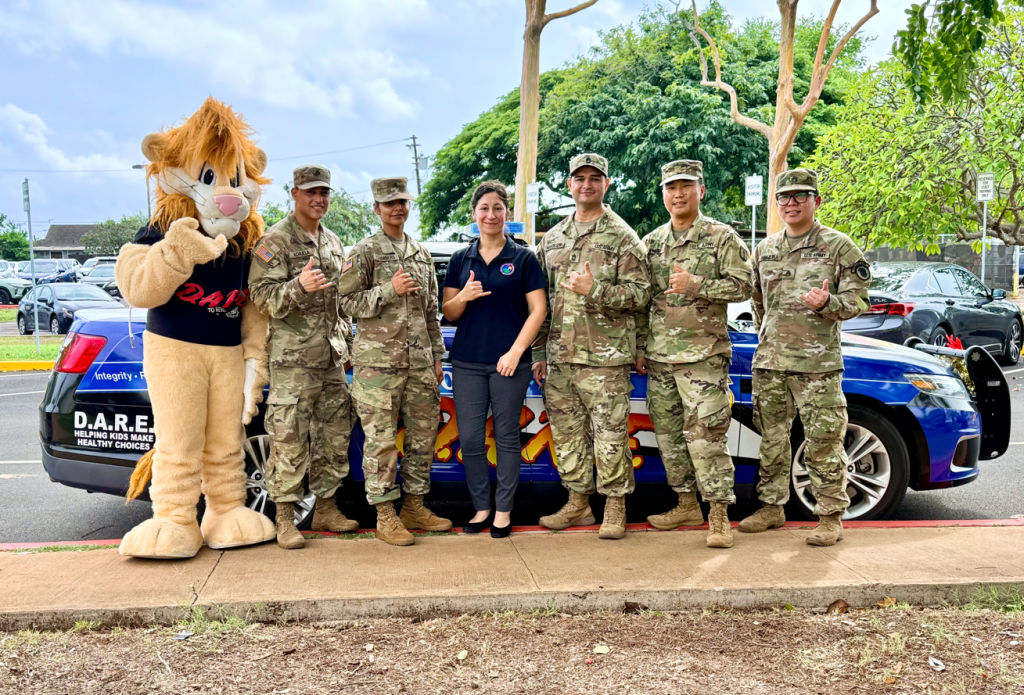 Daren the Lion, Achuela, Chambers, Tech Sgt. Victoria Schlesinger, Sgt. 1st Class Waylen Mendoza, Maj. Brian Kwak and Staff Sgt. Scott Imamura flashed shakas at Iroquois Point Elementary School.