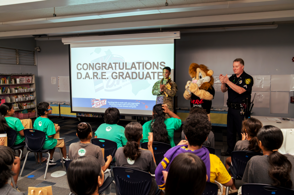 Sgt. Arnold Escano, Daren the Lion and Officer Olmstead congratulated students at Palolo Elementary School