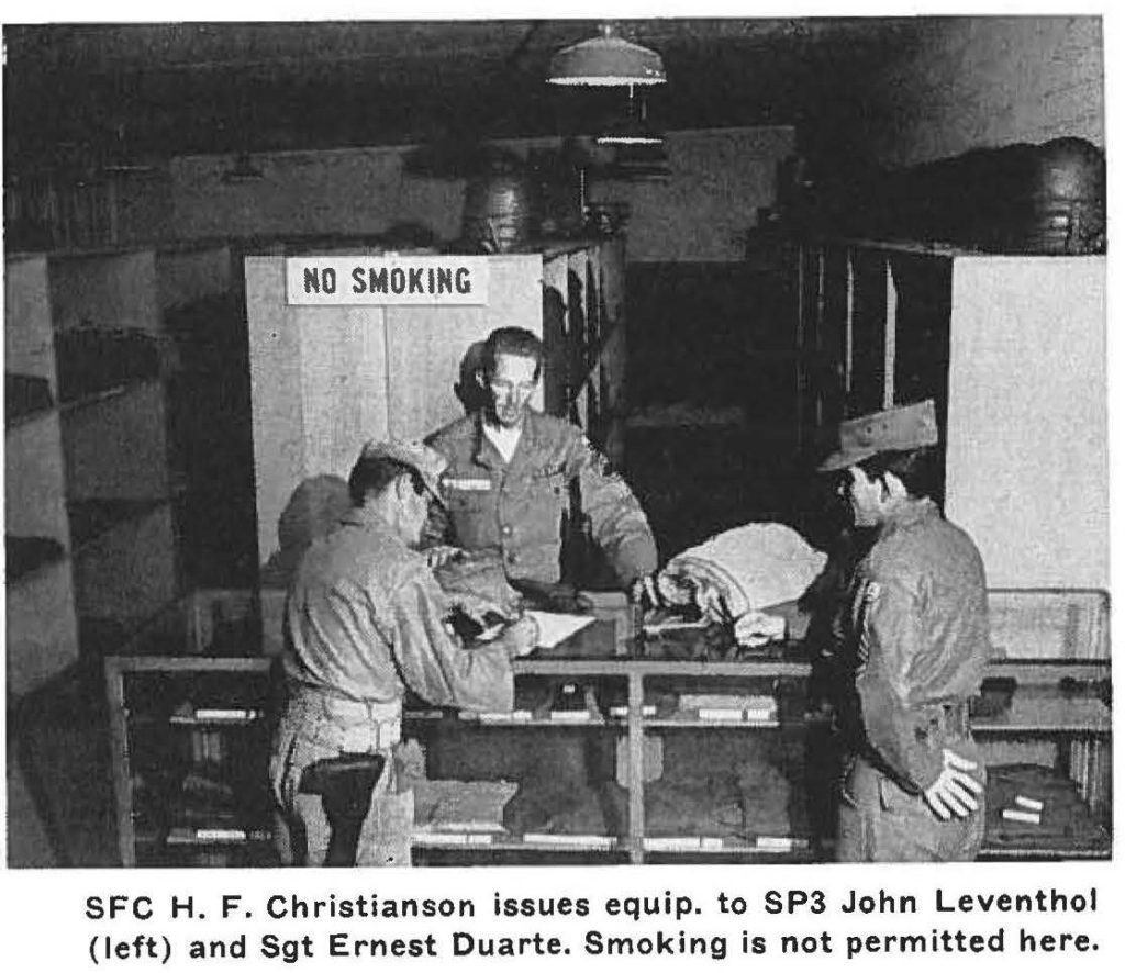 SFC H. F. Christianson issues equip. to SP3 John Leventhal (left) and Sgt Ernest Duarte. Smoking is not permitted here