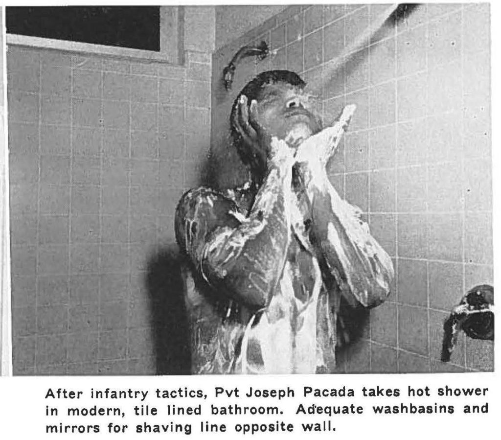 After infantry tactics, Pvt Joseph Pacada takes hot shower in modern, tile lined bathroom. Adequate washbasins and mirrors for shaving line opposite wall