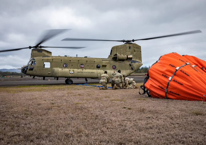 U.S. Soldiers assigned to the 2nd Battalion, 211th Aviation Regiment, Hawaii Army National Guard, secure a Bambi bucket to a CH-47 Chinook during aerial fire suppression water drop operations in response to the Mililani wildfires at Mililani, Hawaii, Nov. 4, 2023. The Hawaii National Guard has conducted over 70 water drops and 30,000 gallons of water over the wildfires in Mililani. (U.S. Army National Guard photo by Sgt. Lianne M. Hirano)